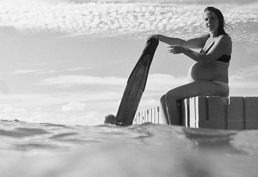 Image of Lucy Van Oosterom with her surfboard on the water