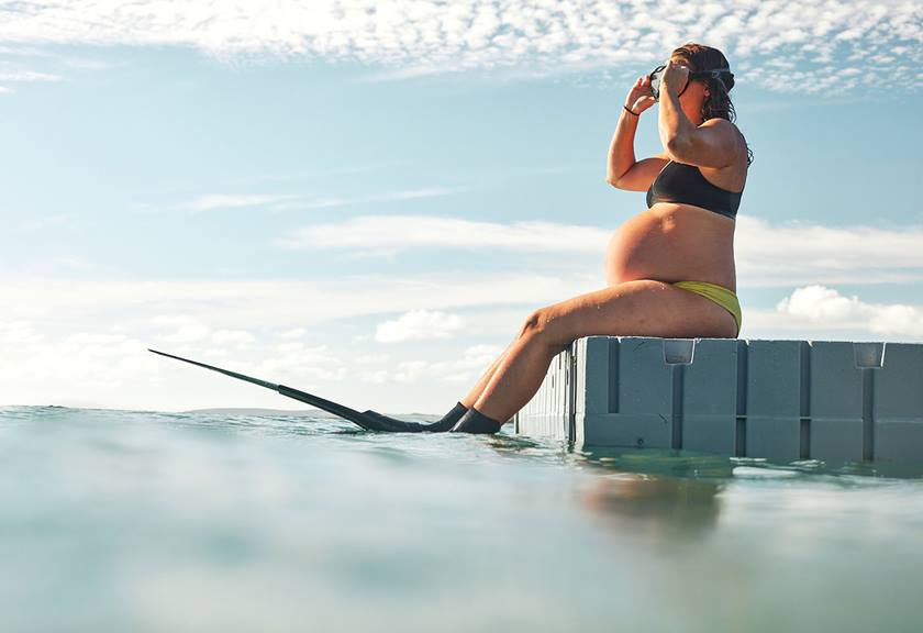 Image of Lucy Van Oosterom with her surfboard and goggles