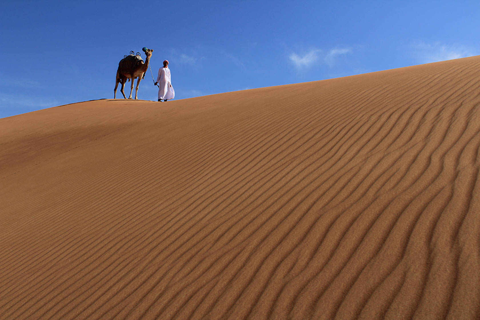 Man leading a camel across the sand dunes taken with Canon EOS 1300D DSLR camera