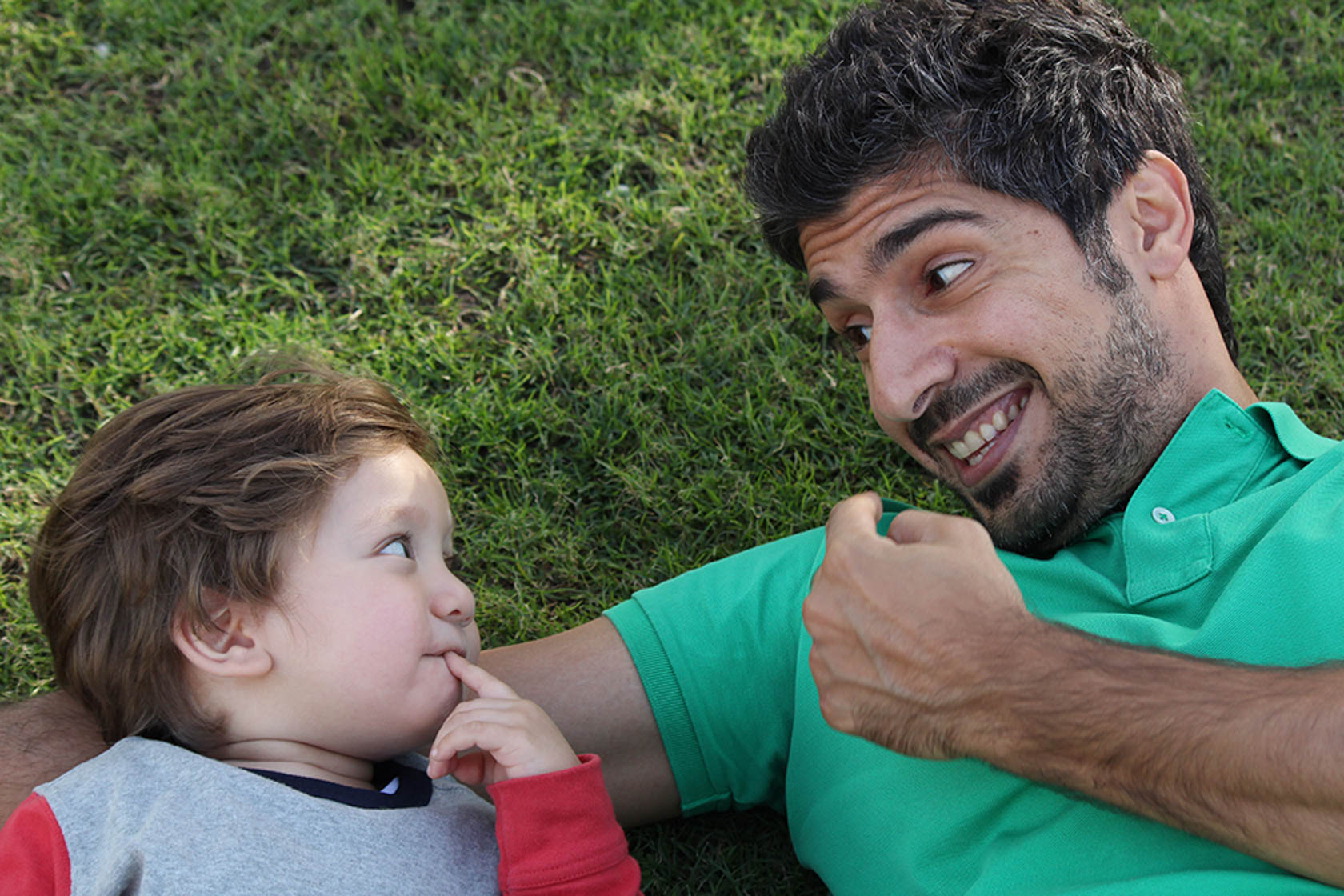 Father and son lying on grass taken with Canon EOS 1300D DSLR camera