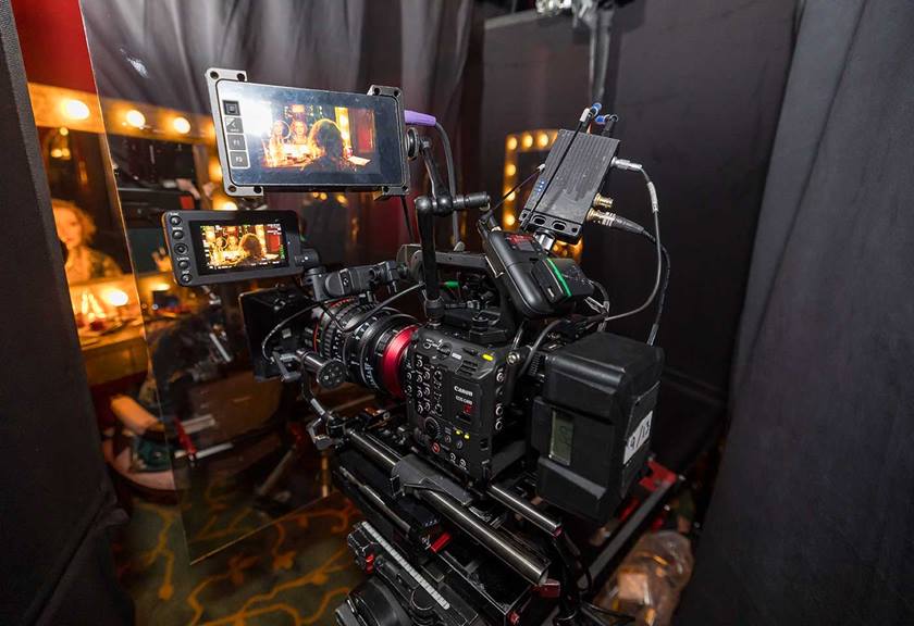A large camera set up with small screens attached, filming a scene of a girl looking into a mirror