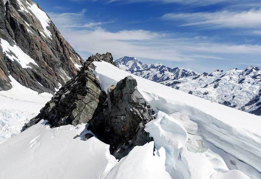 Mountain ranges covered in ice and rock with blue sky and clouds