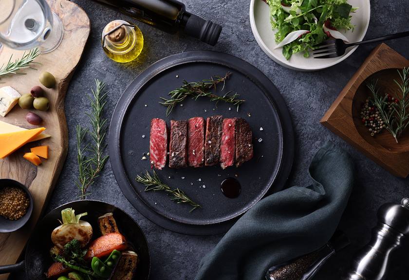 Image of steak garnished on a plate surrounded by other dishes